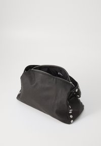 Black leather bag with a zip closure, soft texture, gathered design, and silver circular accents along the sides. Interior visible.
