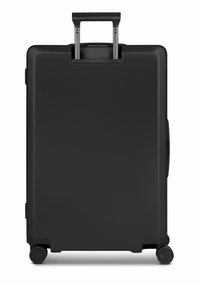Valigia rigida nera con manico retrattile, quattro ruote e una superficie liscia. Presenta un design semplice e una struttura robusta.