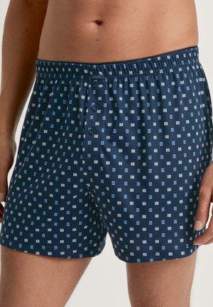 Marineblaue Herren-Boxershorts mit einem Rautenmuster in Hellblau und weißen Akzenten, elastischem Bund und zwei vorderen Knöpfen.