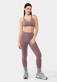 Sujetador deportivo morado con un frente fruncido, combinado con leggings de cintura alta en un tono a juego, ambos con una textura suave.