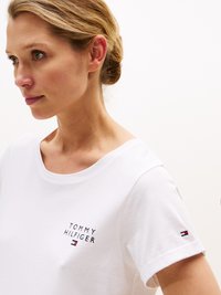 Hvit bomulls t-skjorte med rund hals, korte ermer, og et "Tommy Hilfiger"-logo på brystet med en liten logo på ermet.