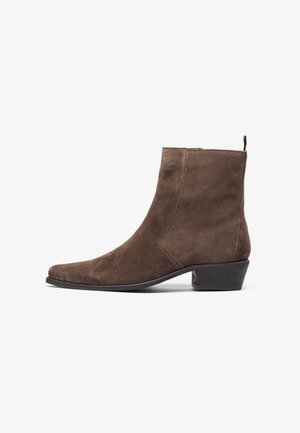 Brown suede ankle boot with a pointed toe, low block heel, and a pull loop at the back for easy wear. Smooth texture and simple design.