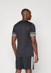 Schwarzes Sportshirt mit grauen Streifen an den Ärmeln; aus einem leichten Stoff gefertigt, mit Rundhalsausschnitt und taillierter Silhouette.