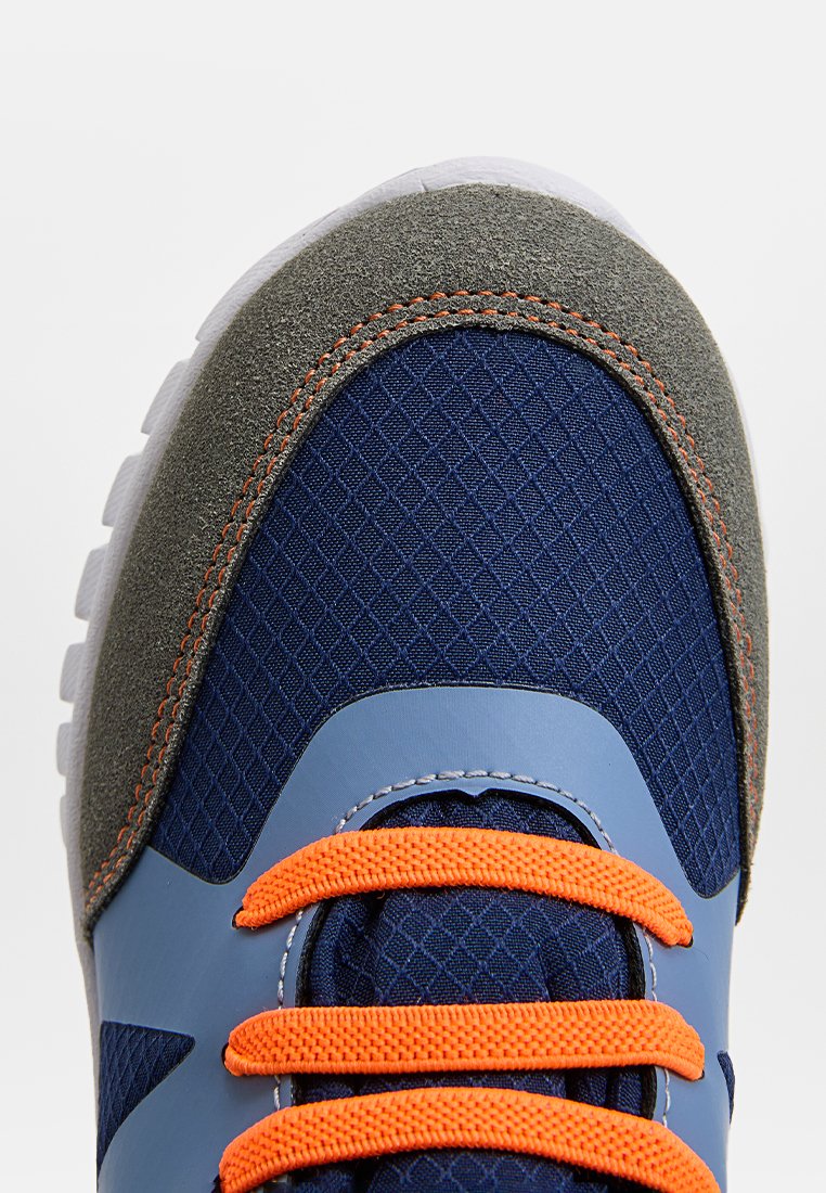 Sportlich geschnürte Schuhe mit einem Obermaterial aus navyfarbigem Mesh, grauen Wildlederakzenten, leuchtend orangefarbenen Schnürsenkeln und einer strukturierten Sohle. Sie verfügen über eine abgerundete Zehenpartie und einen gepolsterten Schaft.
