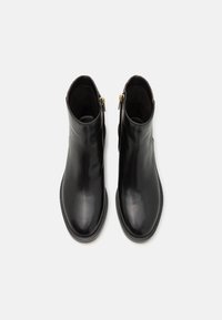 Bottes en cuir noir à cheville avec une texture lisse, un bout arrondi, des fermetures éclair latérales et des semelles en caoutchouc côtelées.