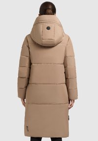 Beige pufferjakke med aftagelig hætte, der har kviltede sektioner og et rundt emblem på ryggen, designet til varme og dækning.