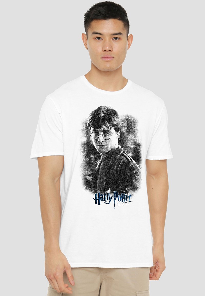 Young man wearing a white T-shirt featuring a black-and-white portrait of Harry Potter with glasses and the "Harry Potter" logo below.
