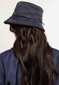 Marineblauwe gewatteerde bucket hat met een brede, flexibele rand en een trekkoord aan de zijkant. Zachte textuur, ideaal voor casual gebruik.