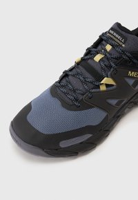 Turistická obuv Merrell s vrchnou časťou z mäkkej sieťoviny v modrej a čiernej farbe, s žltými akcentmi, spevnenou špičkou a textúrovanou gumovou podrážkou pre lepšiu trakciu.