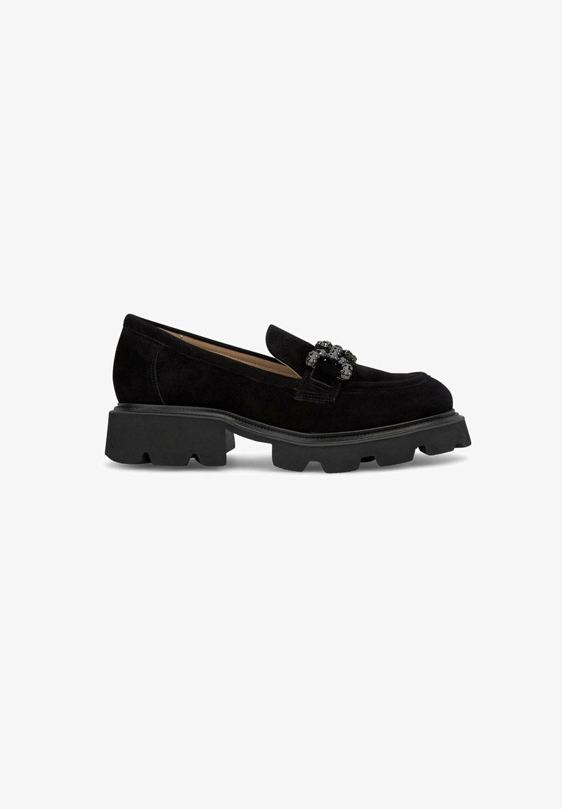 Mocassin en daim noir avec semelle crantée épaisse et boucle décorative noire sur le dessus, vue de côté sur fond blanc uni.