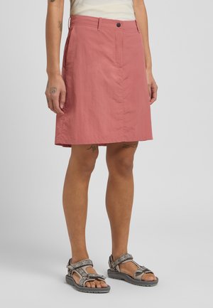 Roze knielange rok van een gladde, lichte stof, met een knoopsluiting aan de voorkant en zijzakken. Gecombineerd met gemêleerde sandalen.