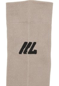 Tessuto lavorato a maglia beige con un logo ricamato nero che presenta tre barre diagonali e una forma angolata a "L".