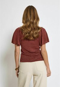 Maroon short-sleeve top with a subtle glitter texture, featuring fluted sleeves and a fitted waist, paired with cream trousers.