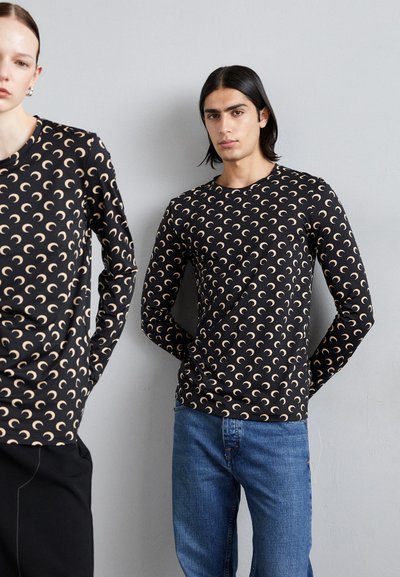 Černé dlouhé rukávy s béžovými vzory v designu půlměsíce, prezentované dvěma modely, kombinované s modrými džíny. Hladká textura látky.