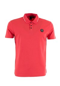 Polo rouge en tissu lisse, avec un col, une patte de boutonnage à trois boutons et un logo noir en cercle sur la poitrine gauche.