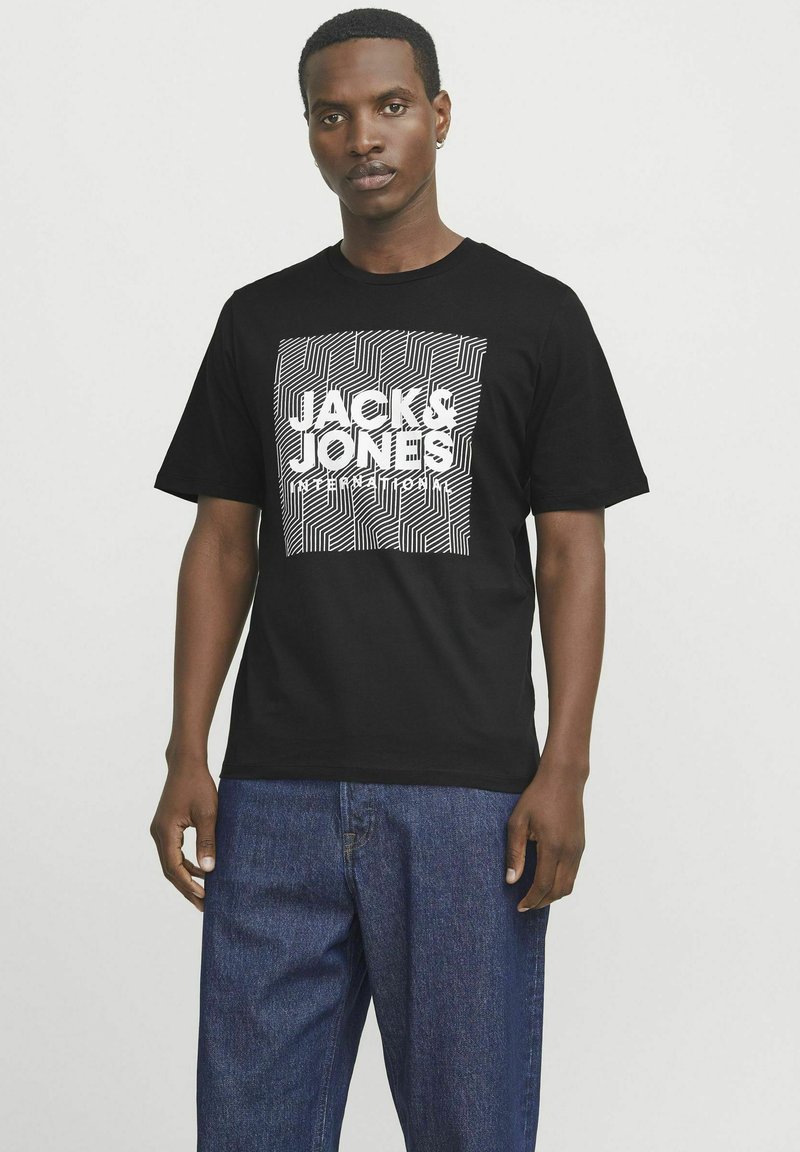 Tricou negru din bumbac, cu un design grafic alb, având modele în zig-zag și textul "JACK & JONES" într-un print pătrat. Guler rotund, mâneci scurte.