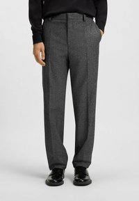 Gray wool trousers with a textured finish, featuring a straight-leg design and pleats, paired with black shoes.