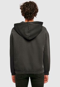 Hoodie gris au toucher doux, avec une capuche à cordon, un ourlet côtelé et des manches longues. Le tissu présente de subtiles variations de teinte.