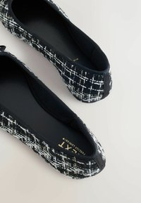 Schwarz-weiße Ballerinas aus strukturiertem Stoff mit kariertem Muster, featuring einem schwarzen elastischen Besatz und einem glatten Innenfutter.