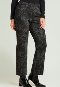 Pantalones con estampado de leopardo en gris oscuro con acabado texturizado, diseño de pierna recta y cintura de tiro medio. Combinados con botines negros.
