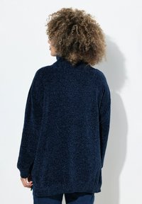 Pullover texture blu navy con collo alto, vestibilità over e spacchi laterali. Tessuto morbido con un aspetto peloso, maniche lunghe.
