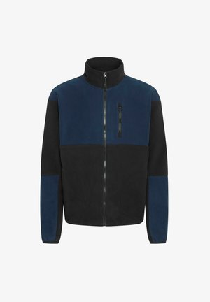 Fliiskjakker, millel on kõrge krae, lukuga sulgemine ja kontrastsed mereväe sinised ning mustad paneelid. Sellel on kaks suurt küljetaskut ja rinnaeelsed taskud.