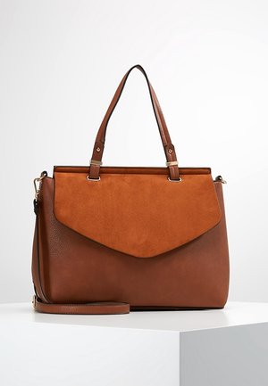 Sac à main en cuir marron avec rabat avant en daim, double poignées supérieures et bandoulière amovible, présenté sur une surface blanche.