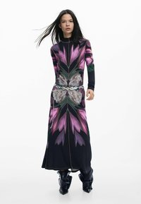 Pikkade varrukatega kleit, millel on erksates värvides lillemustriga trükk, krobelise siluetiga ja vööl metallist kettkaunistus. Musta põhitooniga.