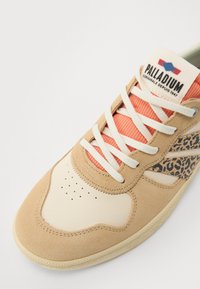 Beige semsket og kremfarget lær sneakers med korallfarget nettingtunge, hvite lisser og en leopardmønsterdetalj på sidepanelet. Merkeforløp synlig.