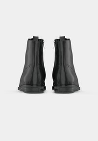 Melnas ādas potītes zābaki ar gludu tekstūru, ar rāvējslēdzēju un dekoratīvām perforācijām sānos. Izturīga melna zole.