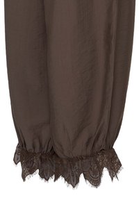 Jambe de pantalon ample en tissu marron avec un poignet élastique et une bordure en dentelle foncée au bas.