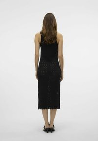 Černé pletené šaty po kolena s texturovaným vzorem a zvlněným lemem, mají přiléhavý střih a bezrukávový design.