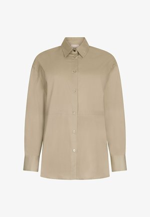 Camisa beige de manga larga con botones, cuello clásico y puños abotonados, mostrada sobre un fondo blanco.