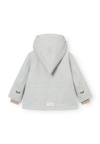 Giacca impermeabile grigio chiaro con cappuccio, polsi elasticizzati e dettagli beige. Presenta un cordino in vita e un'etichetta con il logo vicino all'orlo.