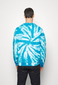 Sudadera de tie-dye azul con un patrón de espiral en diferentes tonos de azul y blanco. Diseño de mangas largas y cuello redondo.