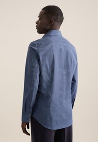 Camicia a maniche lunghe di colore blu scuro con motivo geometrico, polsini abbottonati, colletto e orlo curvo, realizzata in cotone leggero.