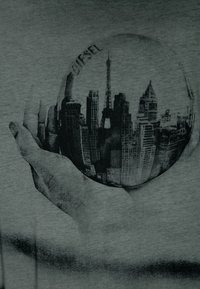 Szary t-shirt z materiału z czarną grafiką przedstawiającą rękę trzymającą glob, odzwierciedlającą miejską panoramę, w tym wieżę Eiffla i wysokie budynki.