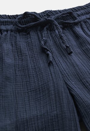 Close-up van donkerblauwe, gestructureerde stoffen shorts met een elastische tailleband en een gebonden trekkoord.