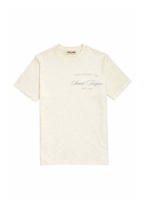 T-shirt beige à manches courtes avec col rond et texte bleu sur la poitrine indiquant « Welcome to Saint Tropez Été 1984 ».