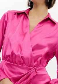 Abito in satin rosa con colletto, design avvolgente e vita arricciata. Presenta bottoni decorativi sul lato e una texture liscia e lucida.