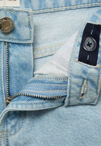 Light blue denim with a silver metal zipper, button closure, and inner cotton lining. Features stitched detailing and a navy fabric accent.