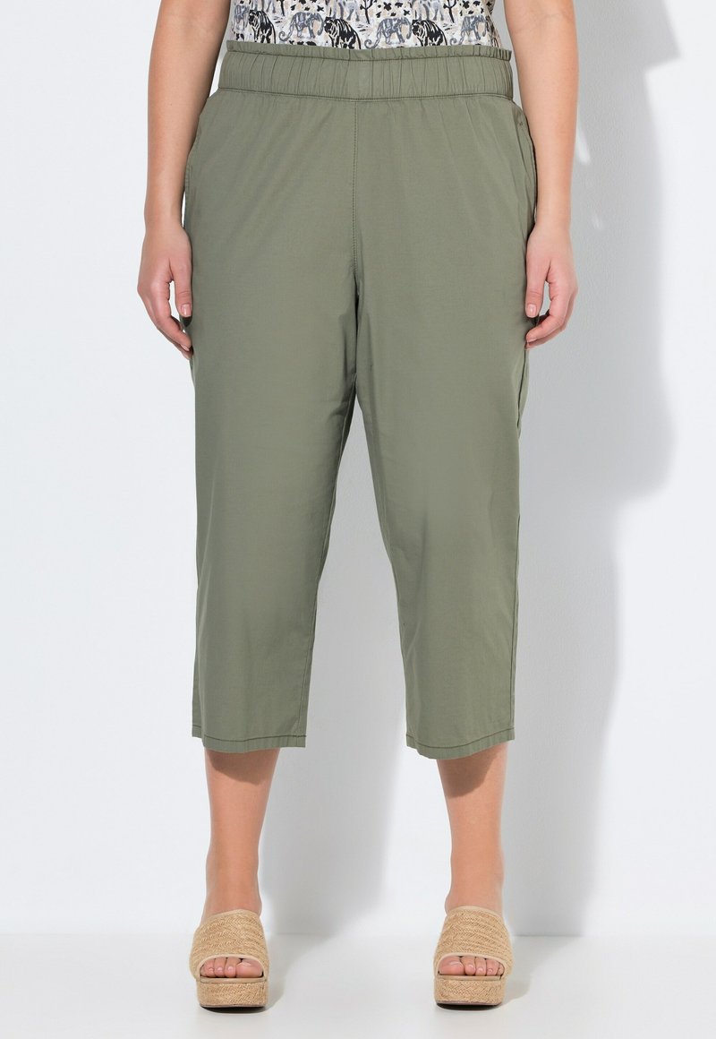 Olijfgroene, lichte, cropped broeken met een elastische tailleband. Bevat zijzakken en heeft een losse pasvorm, gecombineerd met platform sandalen van natuurlijke vezels.