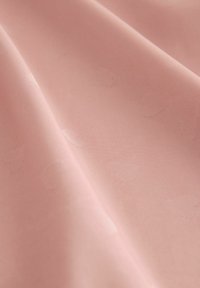 Vaaleanpunainen kangas, jossa on hienovarainen sydänkuvio, sileä pinta ja pehmeä kiilto, soveltuu erilaisiin tekstiilisovelluksiin.