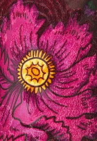Bright pink and purple fabric with a large embroidered flower featuring a yellow and orange sun-like center.