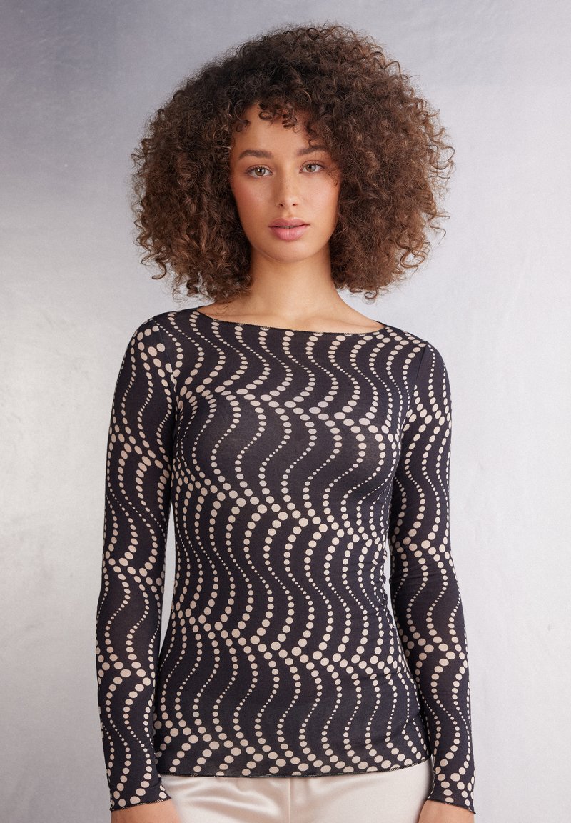 Zwarte longsleeve top met een golvend patroon van beige stippen. Gemaakt van een soepele, rekbare stof, heeft hij een brede halslijn en een slanke pasvorm.