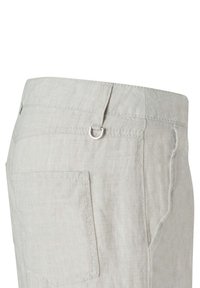 Pantaloni in lino beige chiaro che mostrano la tasca posteriore, il passante per la cintura e un piccolo dettaglio in D-ring argentato in vita.