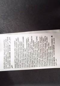 Etiqueta de cuidado con instrucciones de lavado en varios idiomas, aconsejando lavar con colores similares en una superficie oscura.