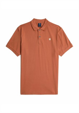 Polo de manga corta en color naranja quemado, con una tapeta de dos botones, cuello acanalado y un pequeño logo en el pecho. Textura de algodón suave.