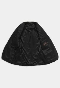 Zwarte blazer met een satijnen binnenvoering, met een gladde textuur, scherpe revers en zijzakken. De binnenstof toont een subtiel patroon.