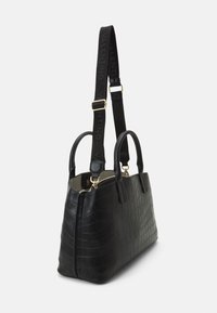 Svart krokodilprickad läderväska med rundade handtag, justerbar rem, guldfärgad hårdvara och dragkedjestängning upptill.